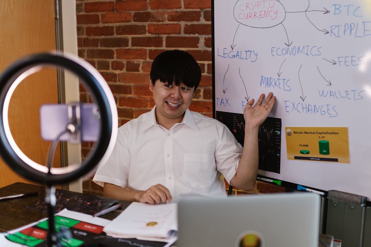 Asian man explaining cryptocurrency market with whiteboard indoors.